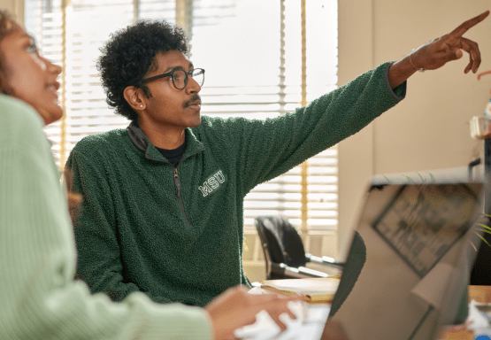 Two JMC students working together behind a computer.