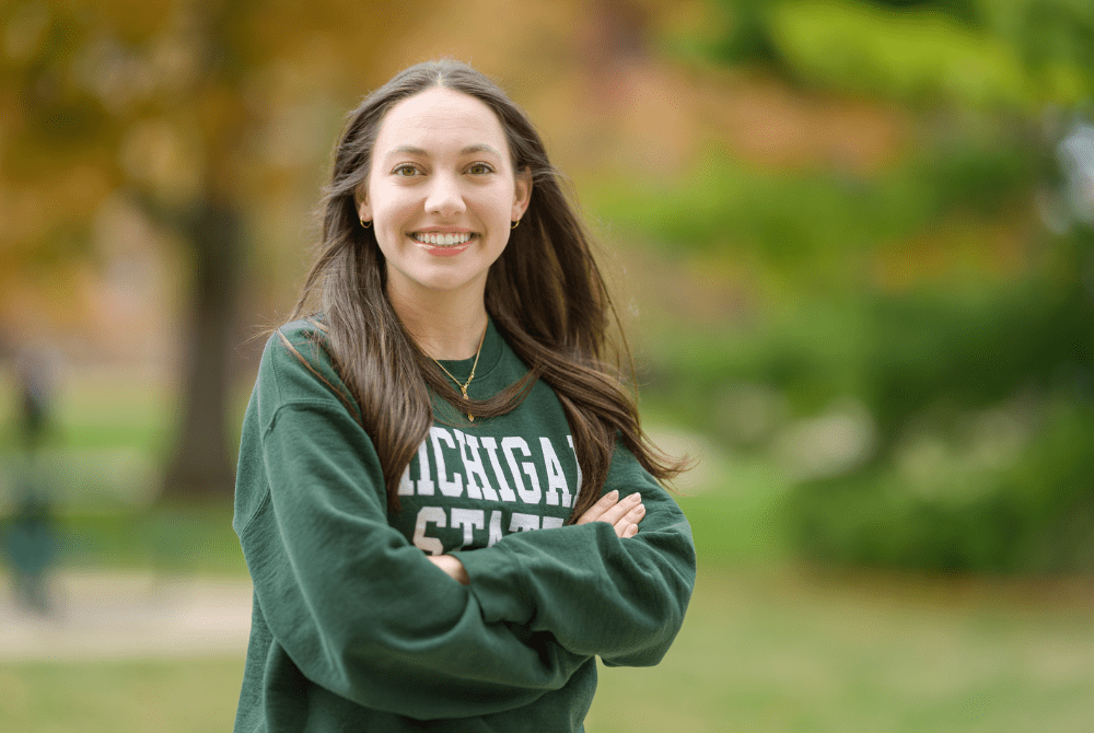 JMC student Taylor Regester, photographed outside wearing a green Michigan State sweatshirt.