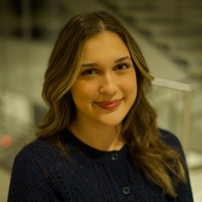 Professional portrait of a JMC student, who is wearing a black cardigan and is smiling at the camera.