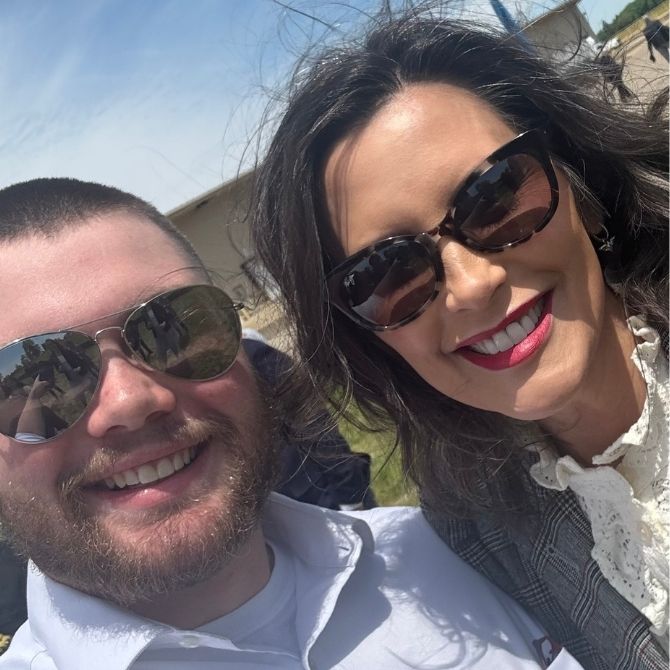 Selfie of JMC student and Michigan Governor Gretchen Whitmer. Both are wearing sunglasses, posing outside on a sunny day.