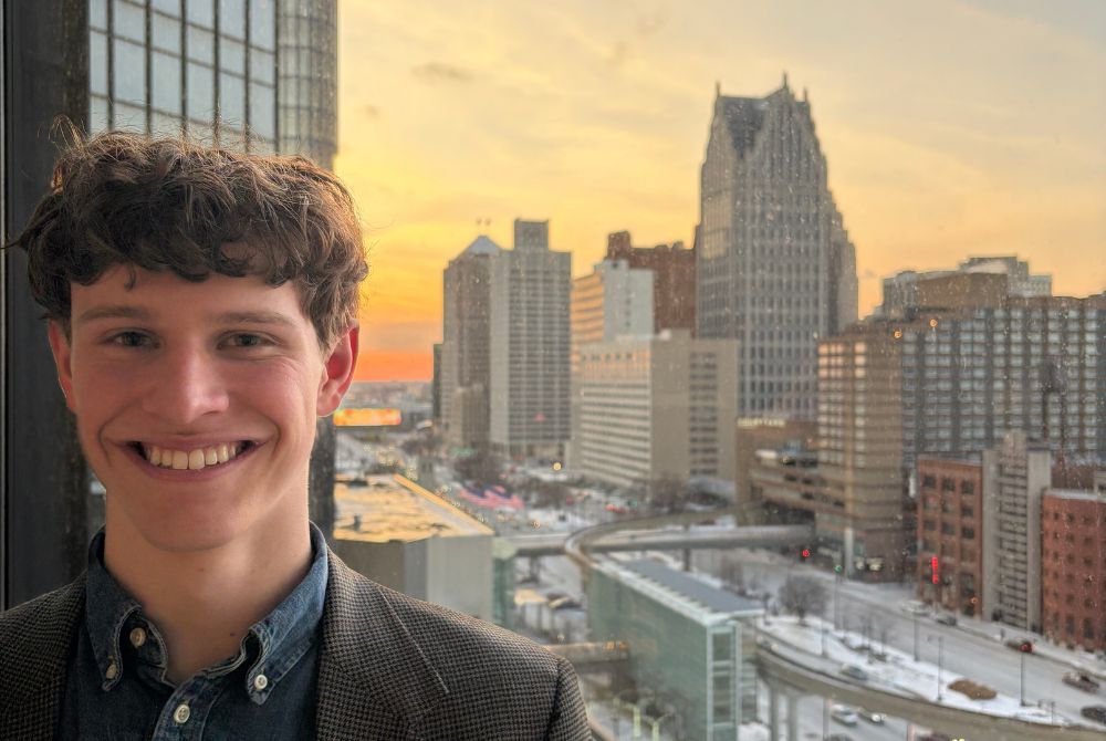 JMC student Ethan Czaja posing in front of the skyline outside of the Canadian Consulate in Detroit