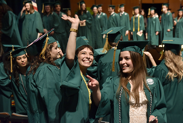 graduates smiling and some walking across stage to receive diplomas