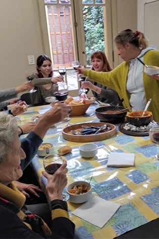 Several people sit at a table and toast with glasses of wine