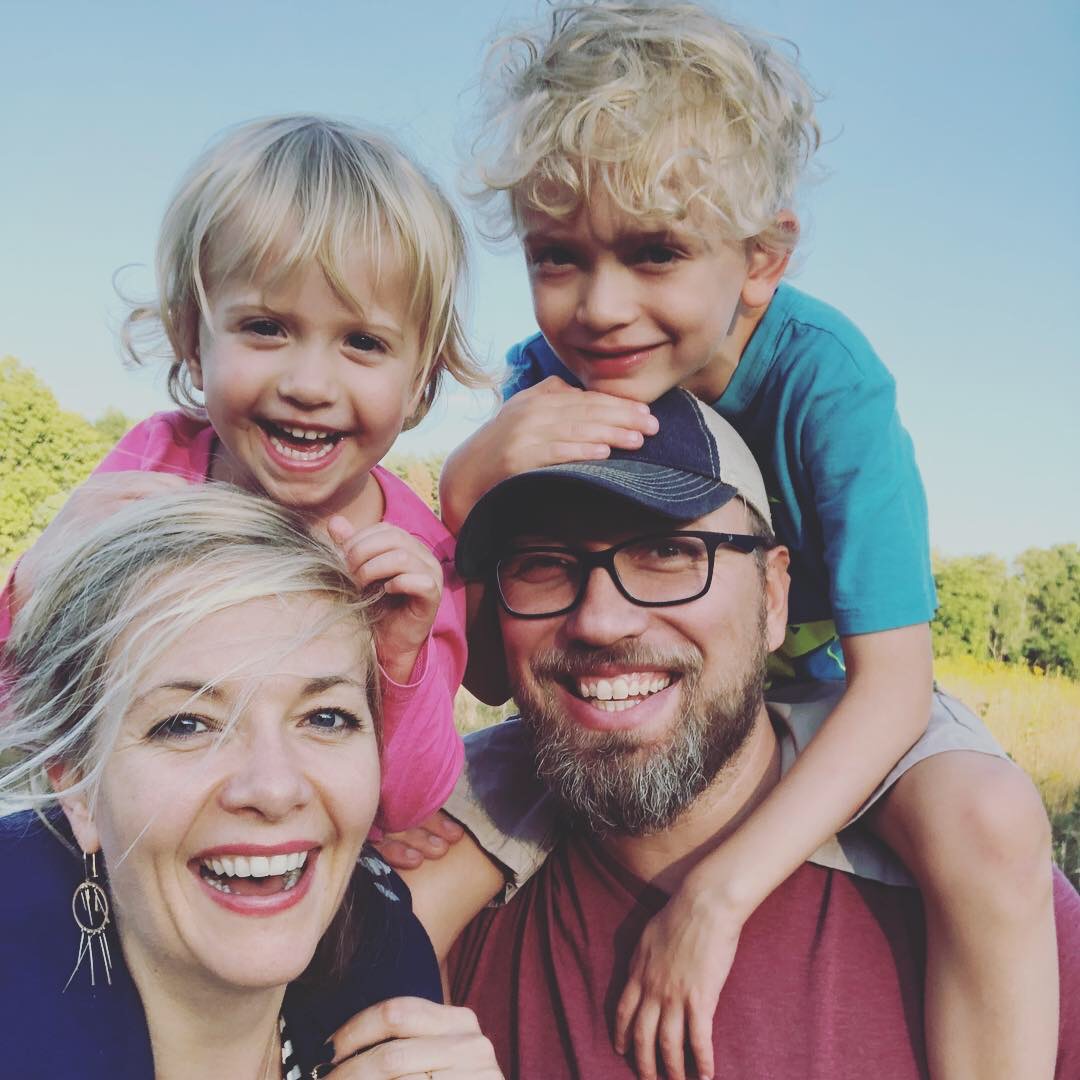 two adults with two children; each child is sitting atop of an adult's shoulders