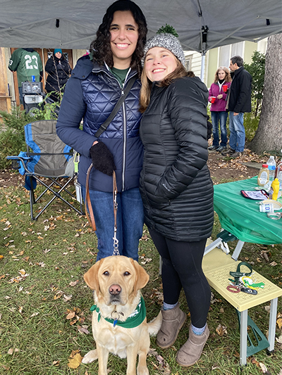 Two women and dog standing under an outdoor tent