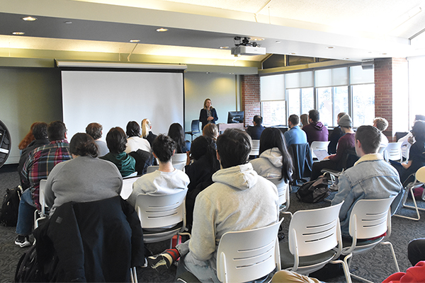 Club Spartan, students seated in rows looking toward front of the room with woman speaking near podium