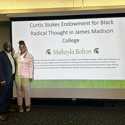 woman and man stand off to side of screen displaying award information