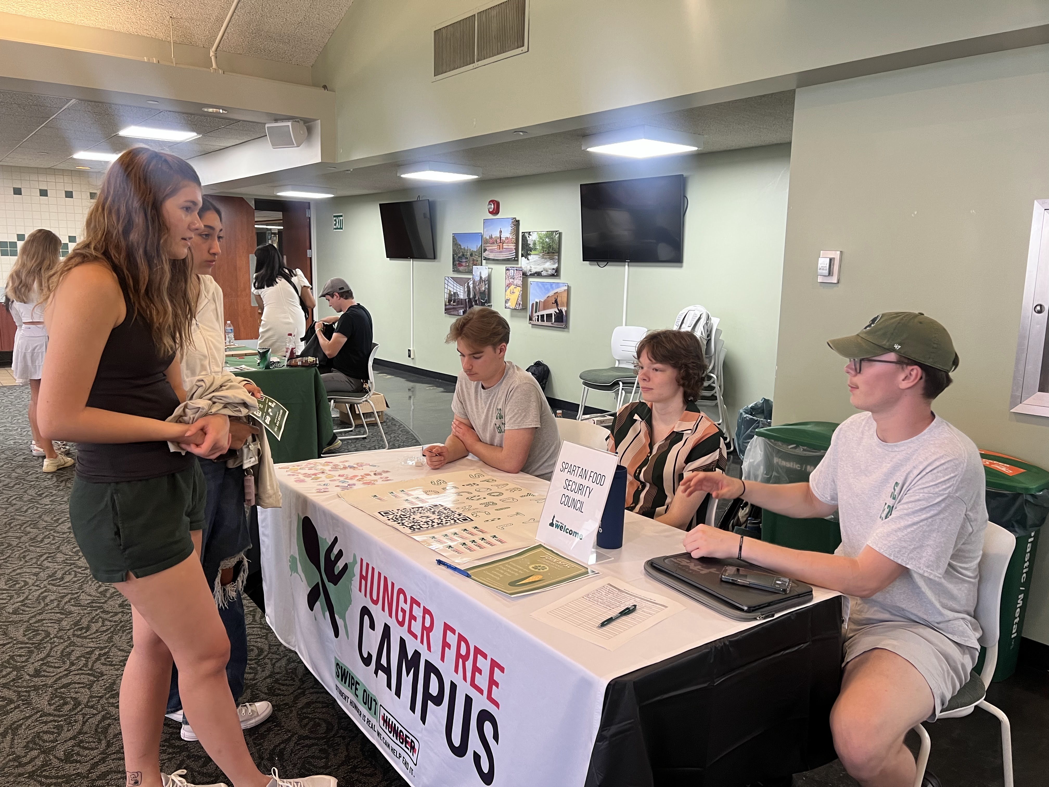 students standing and speaking to other students seated at a table