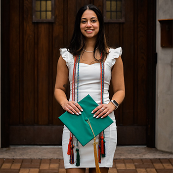 Portia Chana stands in front of Beaumont Tower with her graduation cap