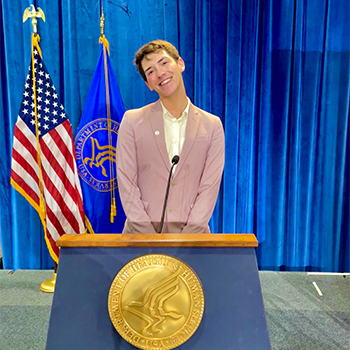 Stevie standing at a podium with the American flag left side