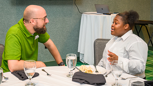 two people sitting at a table speaking