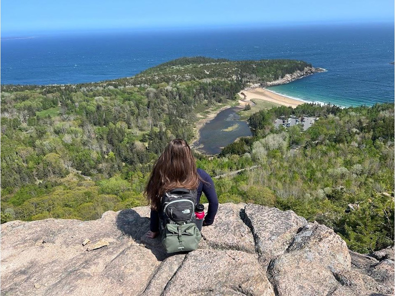 Back of person seated looking out over mountain at water