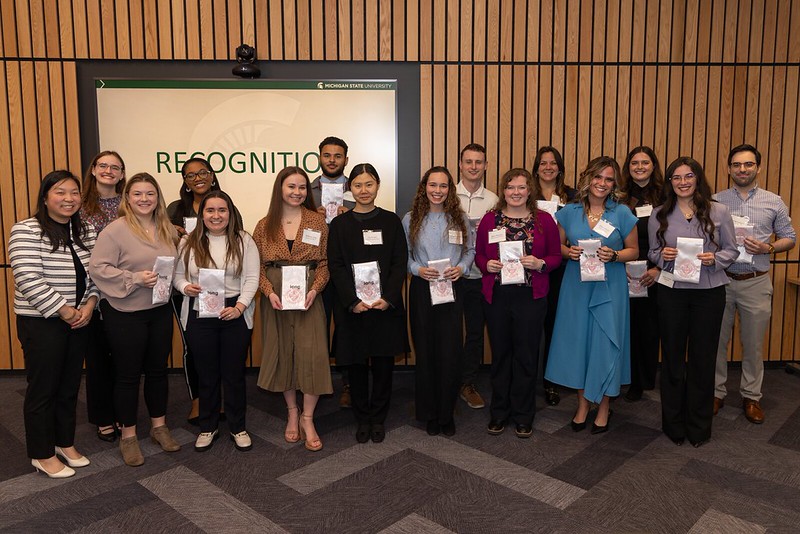 Members of the Class of 2026 IRL editorial board pose together in front of a presentation screen, with several holding commemorative stoles.