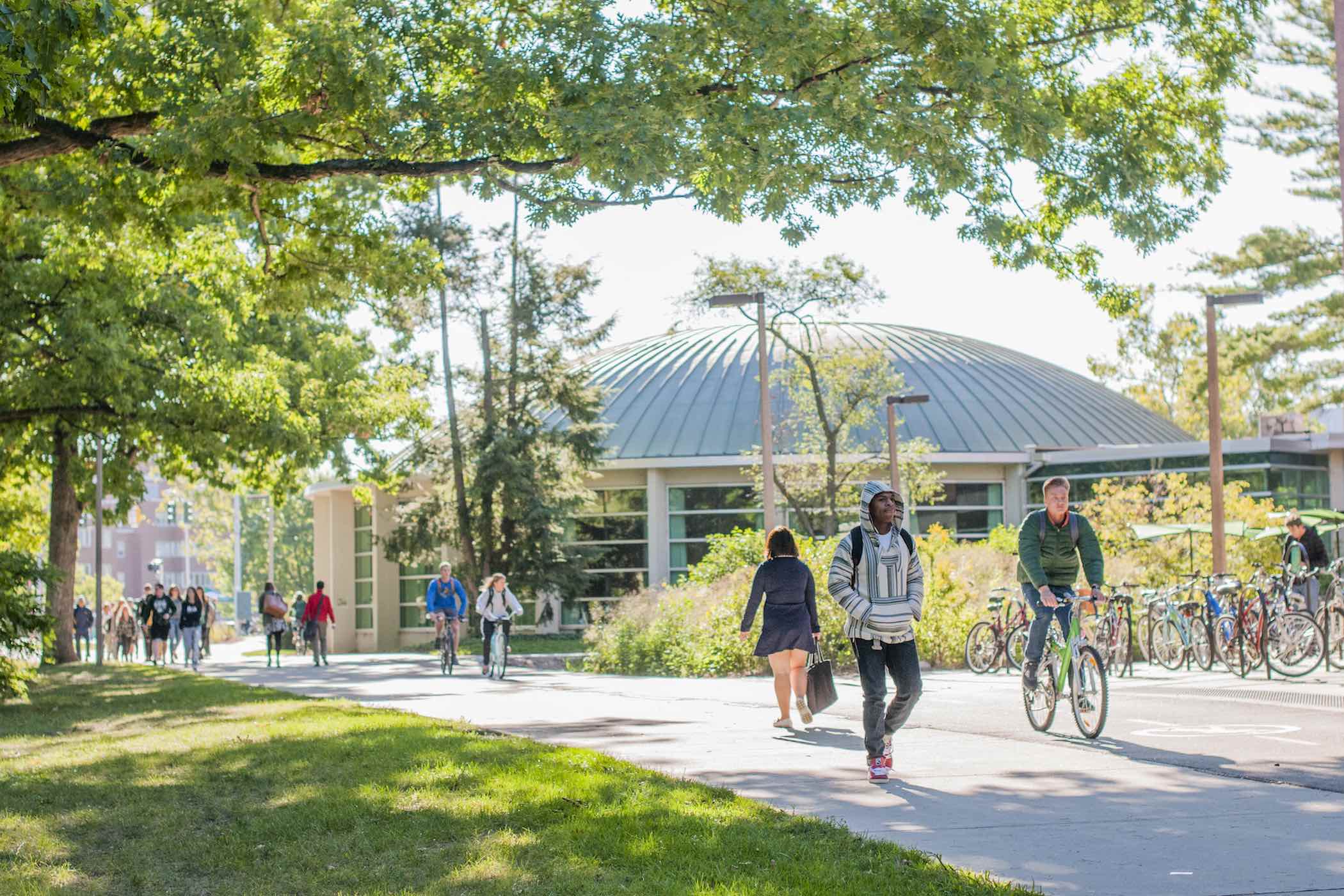 Students walking along the Red Cedar River on a sunny day.