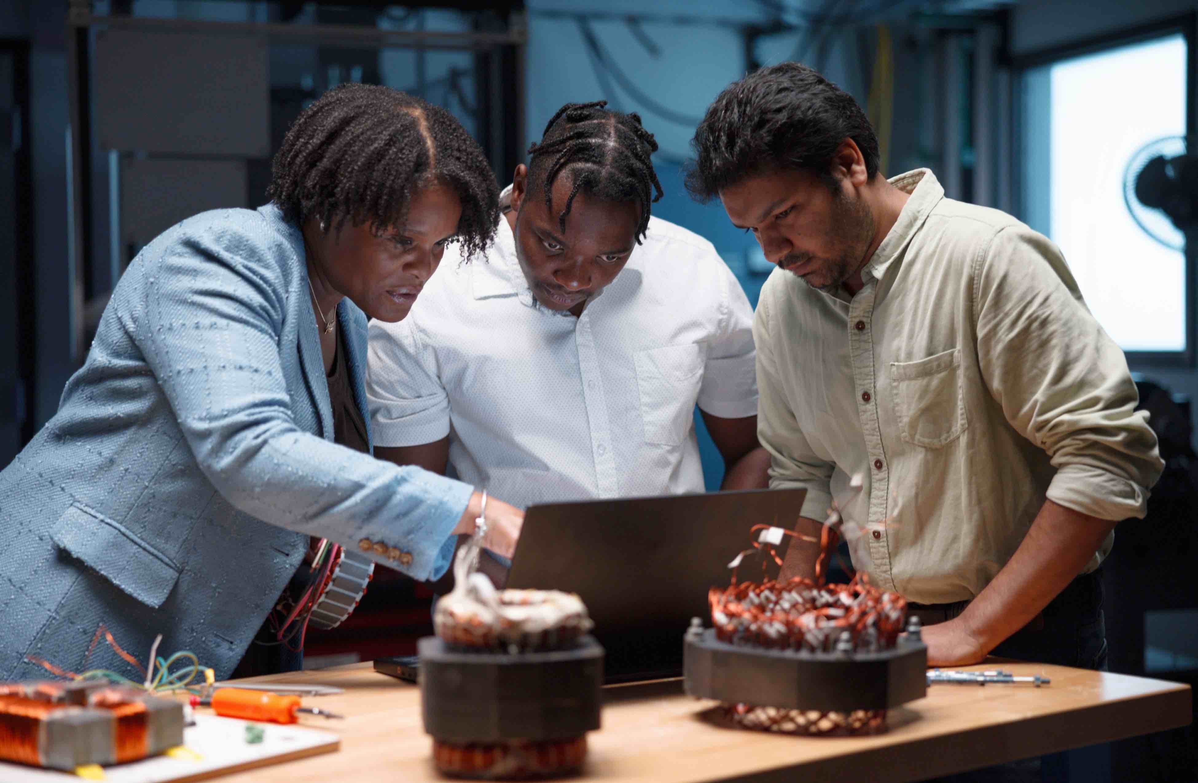 Three people in a lab looking at a laptop.