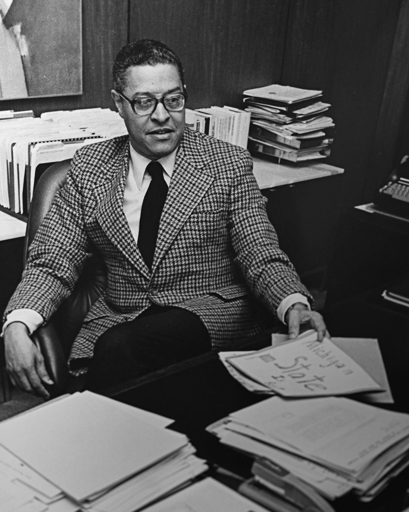 Wharton sitting at desk with papers