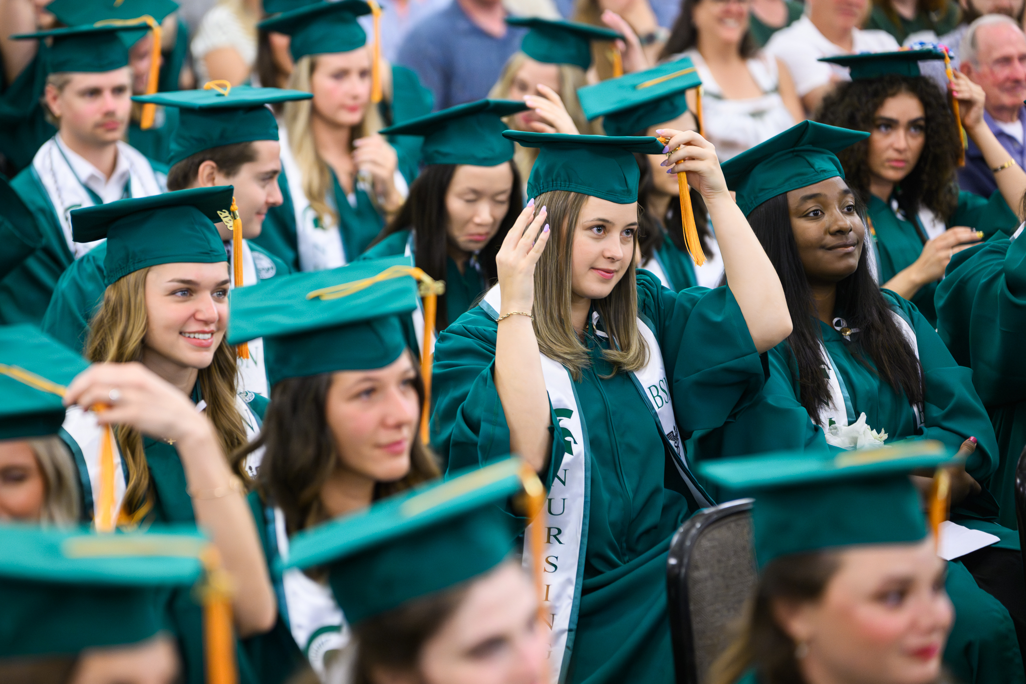 Students in caps and gowns sitting at graduation.