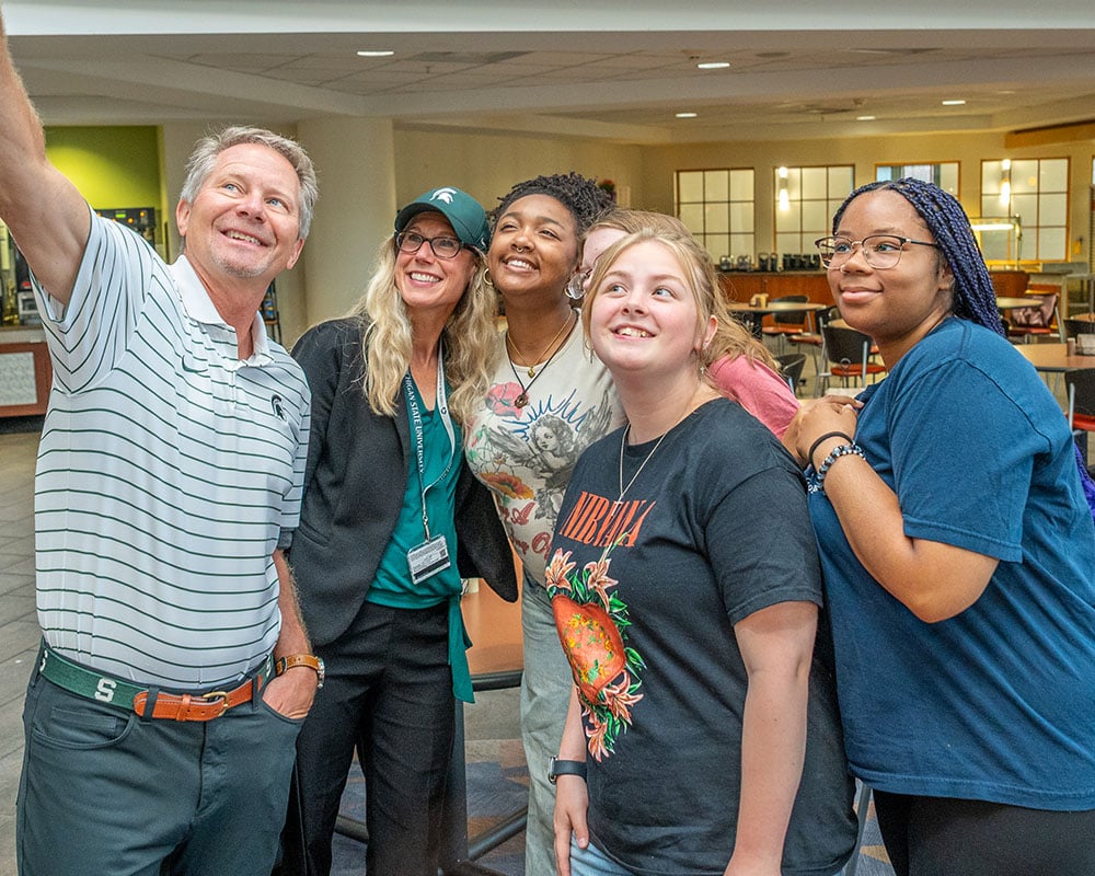 MSU president and provost stand with a group of students taking a selfie.
