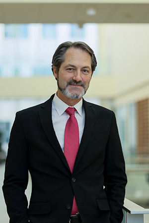 MSU Department of Pediatrics and Human Development professor and Associate Chair for Research Andre S. Bachmann, PhD dressed in a black suit, white shirt, and a red tie, posed inside the College of Human Medicine's Grand Rapids Research Center