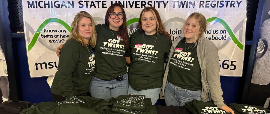 A group stand linked arm in arm behind a table with matching t-shirts.