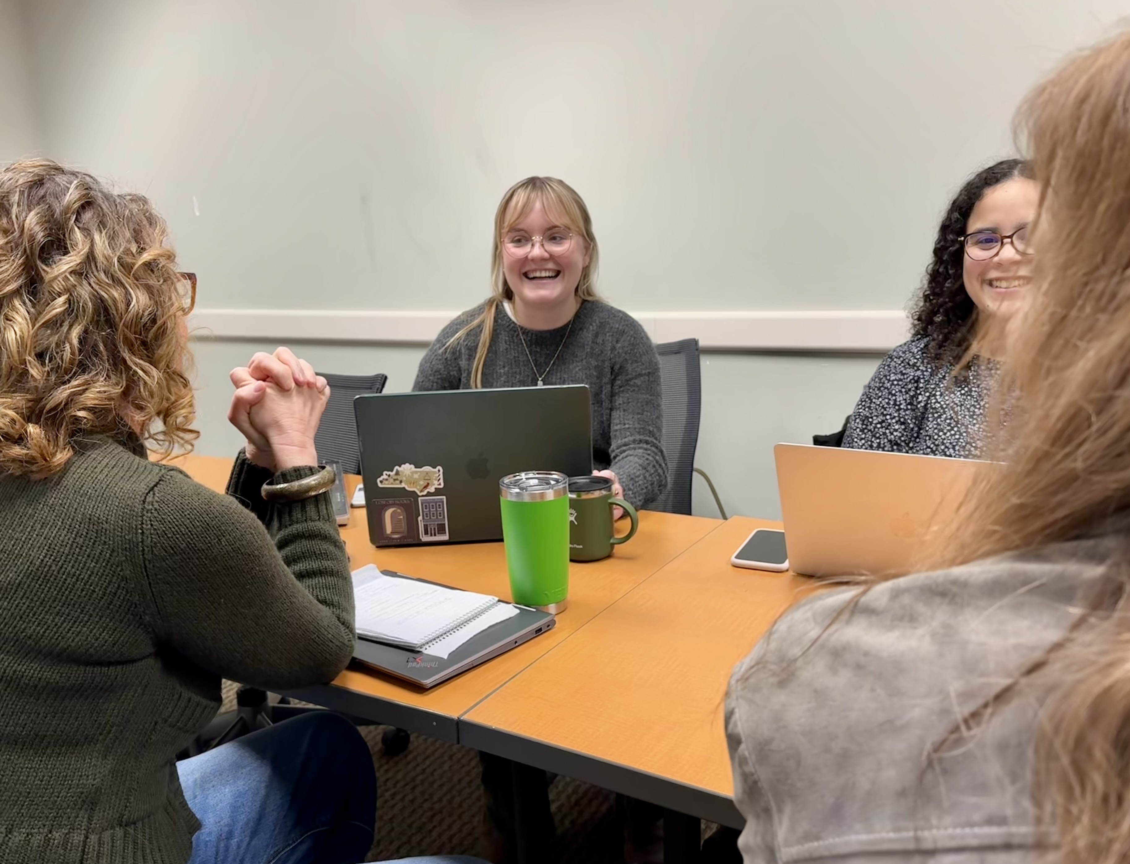 A group of students talk around a table.