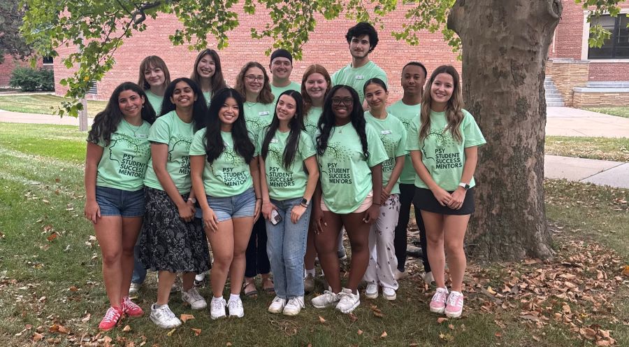 A group of people stand in front of a tree with matching t-shirts.