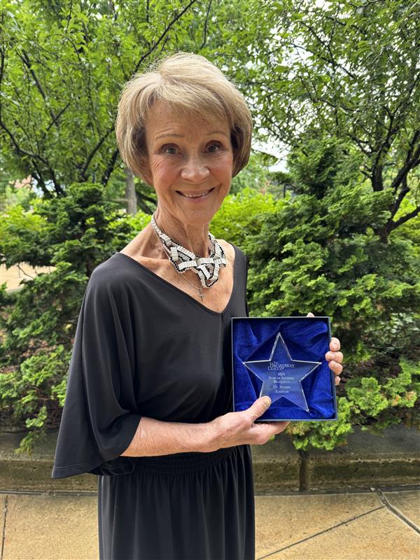 Bonnie Knutson stands smiling with the 2025 Star of Touring Broadway Award.