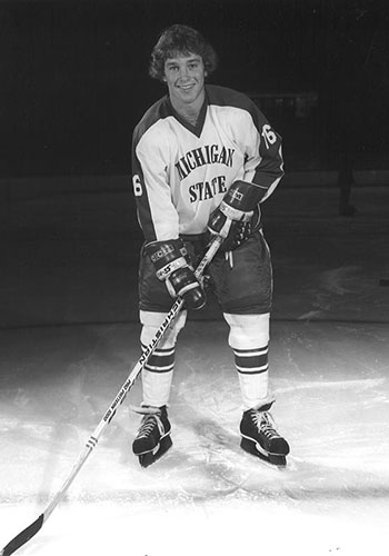a black-and-white image of MSU hockey alum Gary Harpell, posing on the ice, dressed in his full MSU Hockey uniform