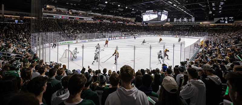 a view from the stands at Munn, showing the entire arena filled with people, while a hockey game is in progress on the ice