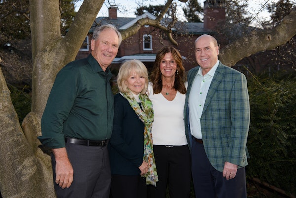 Group portrait of the MSU Uncommon Will, Far Better World campaign co-chairs outdoors beneath trees on campus.