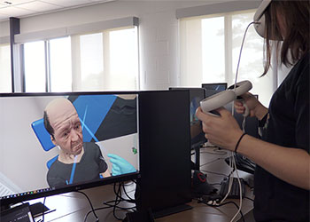 A student uses as VR headset to perform a simulated procedure on a "patient" through an interactive computer program.