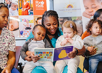Family members read a story to a group of small children.