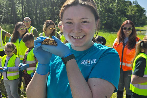 Dana MacCallumMhor poses outside with a Blanding's turtle in front of a group of volunteers who will assist in the turtles' release back into the wild.