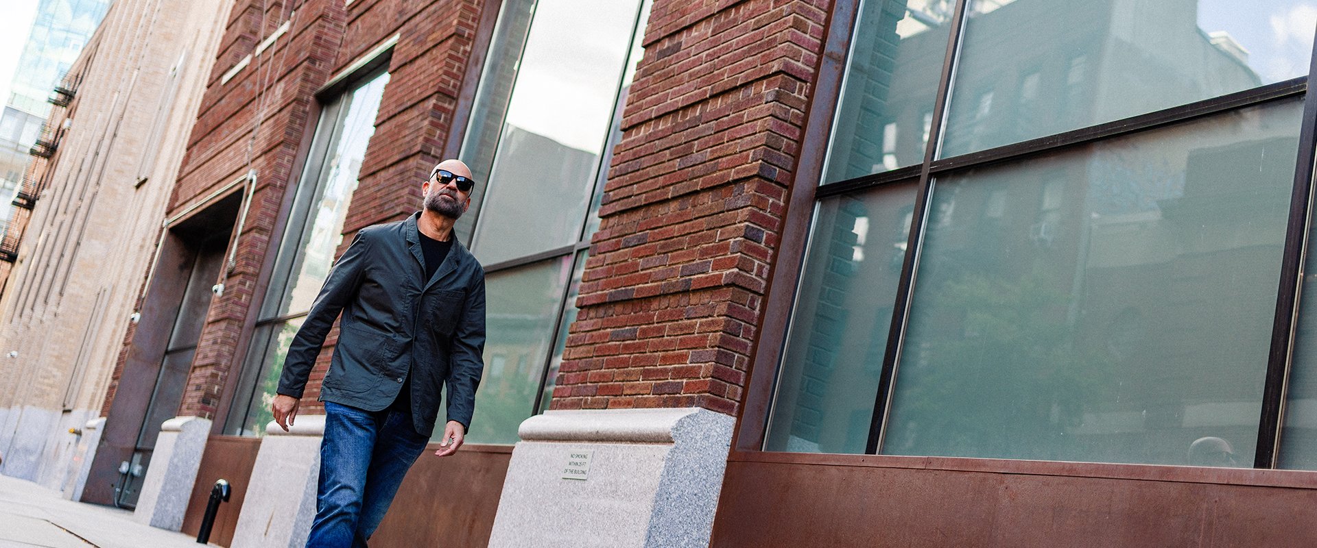 Paul Rosenberg walking past a brick and glass building