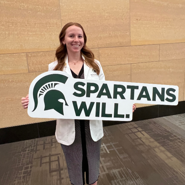 MSUCHM student Jenna Koelsch holding a big Spartans Will sign