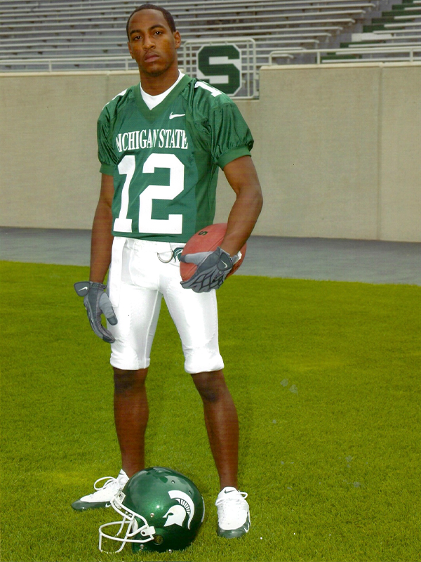 Jeremy Orr posing with a football in his uniform in Spartan Stadium.