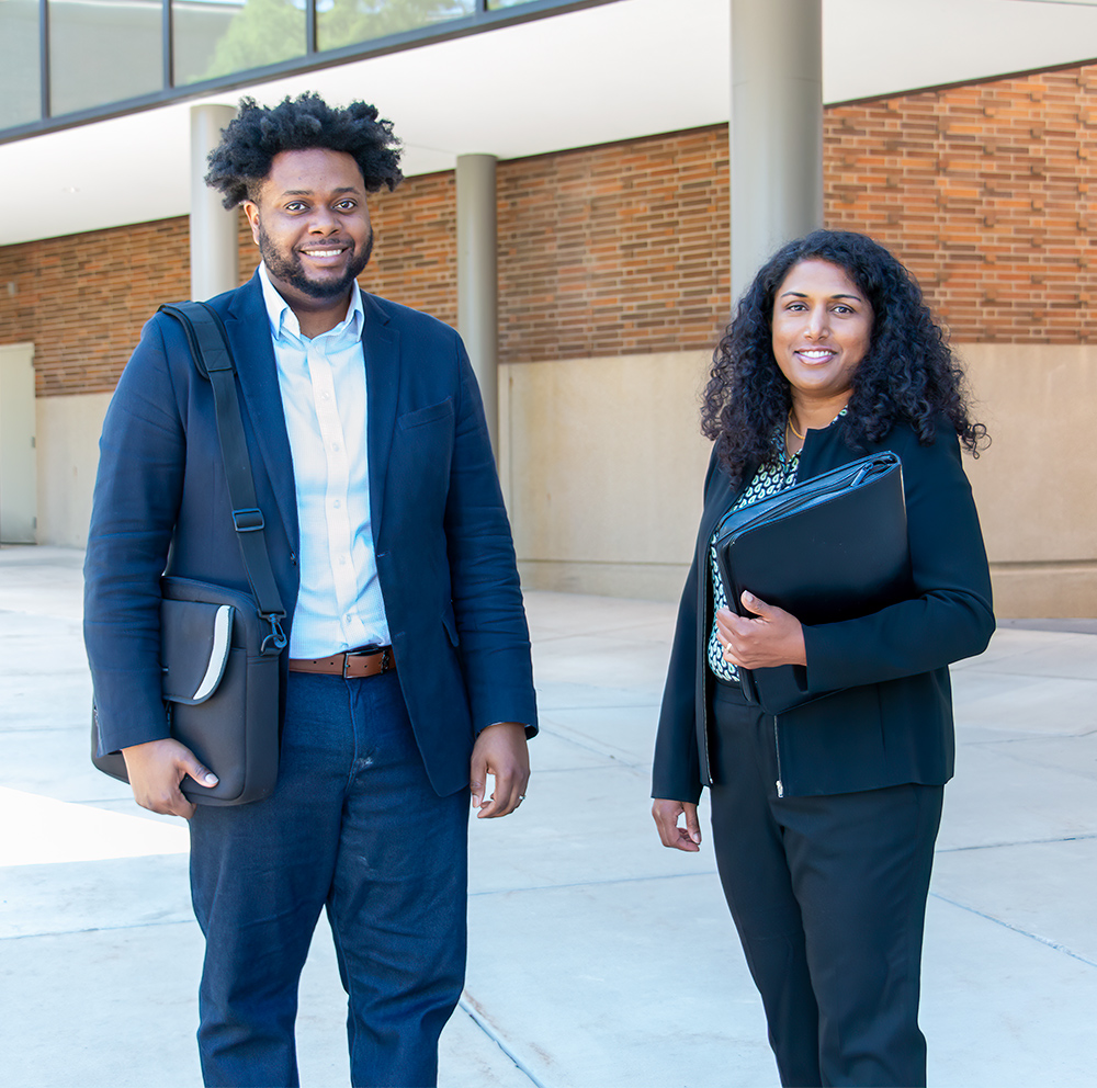Two professionals from the MSU School of Social Work smile outside a campus building.