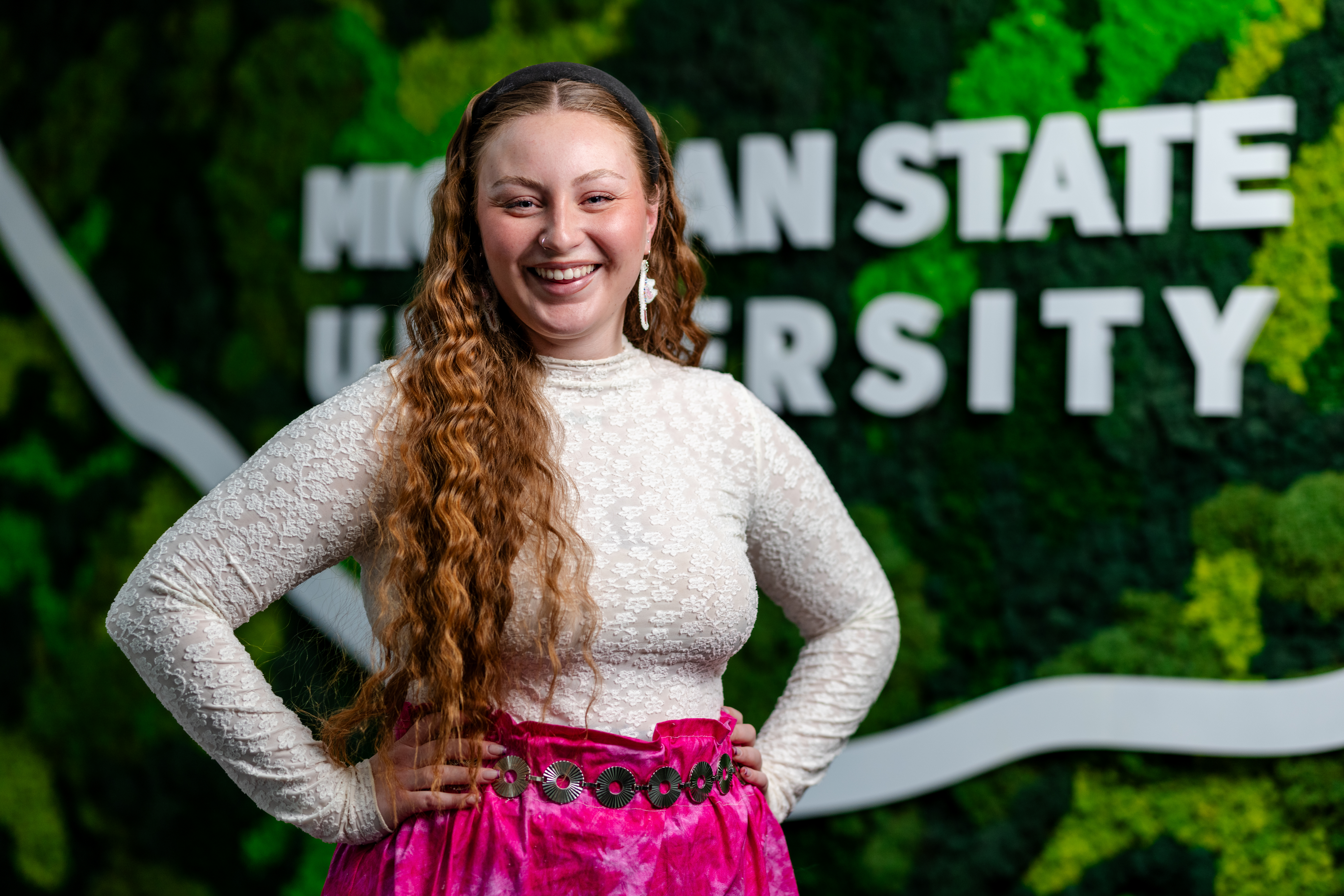 A portrait of Kaylin Casper smiling at the camera in front of a green and white MSU background.