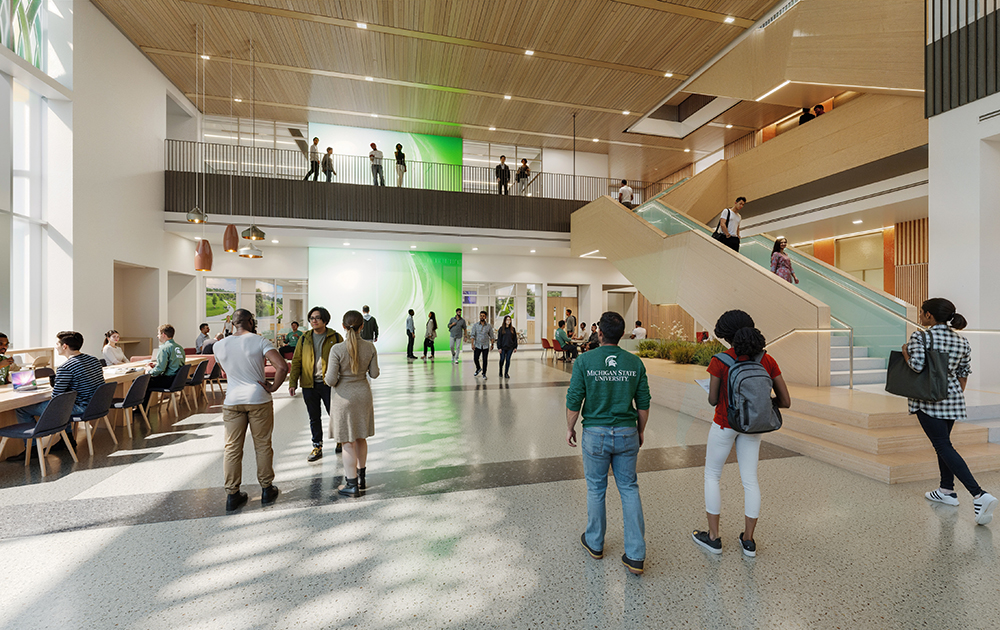 Students and visitors walk through a bright, modern building lobby with seating, stairs, and a green-lit feature wall.