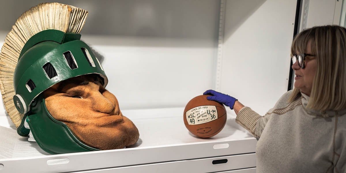 A decades-old Sparty mascot head and commemorative 1951 basketball sit in a collections cabinet at the MSU Museum.