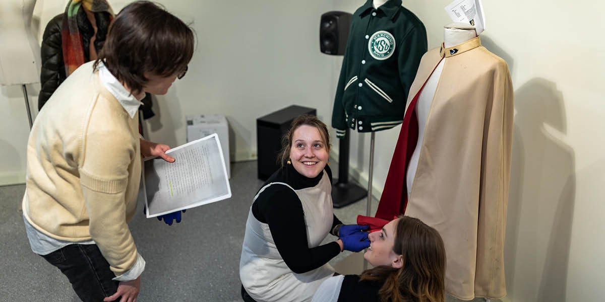 Students in the Museum Studies course at the MSU Museum inspect vintage clothing.