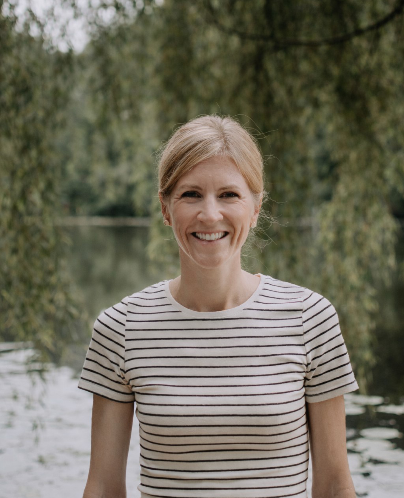 Headshot of Alumna Brooke Larm, outdoors in front of a pond