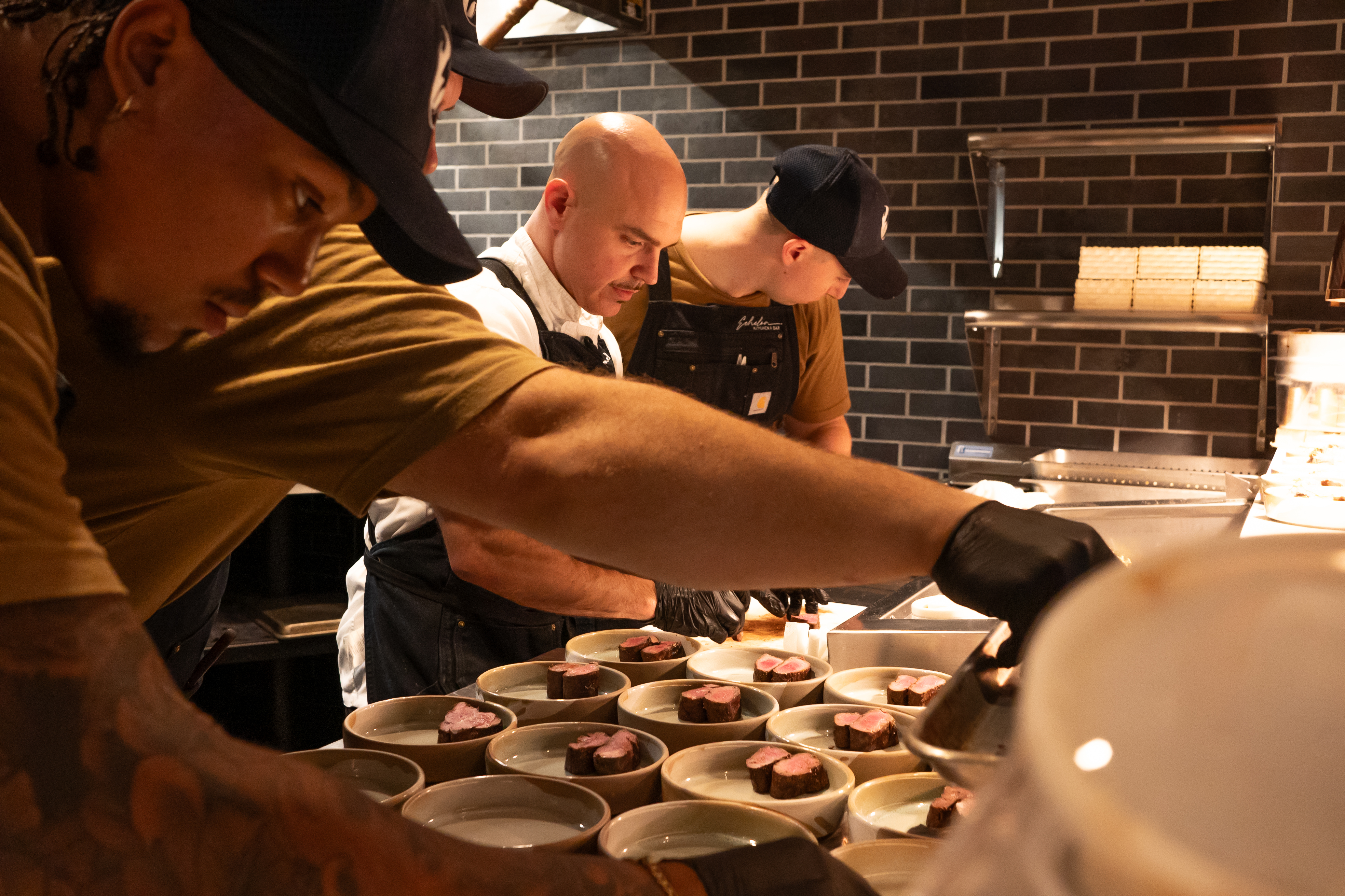 Executive chef Joseph VanWagner, '09, prepares food with his staff in the red-bricked kitchen at Echelon Kitchen & Bar.
