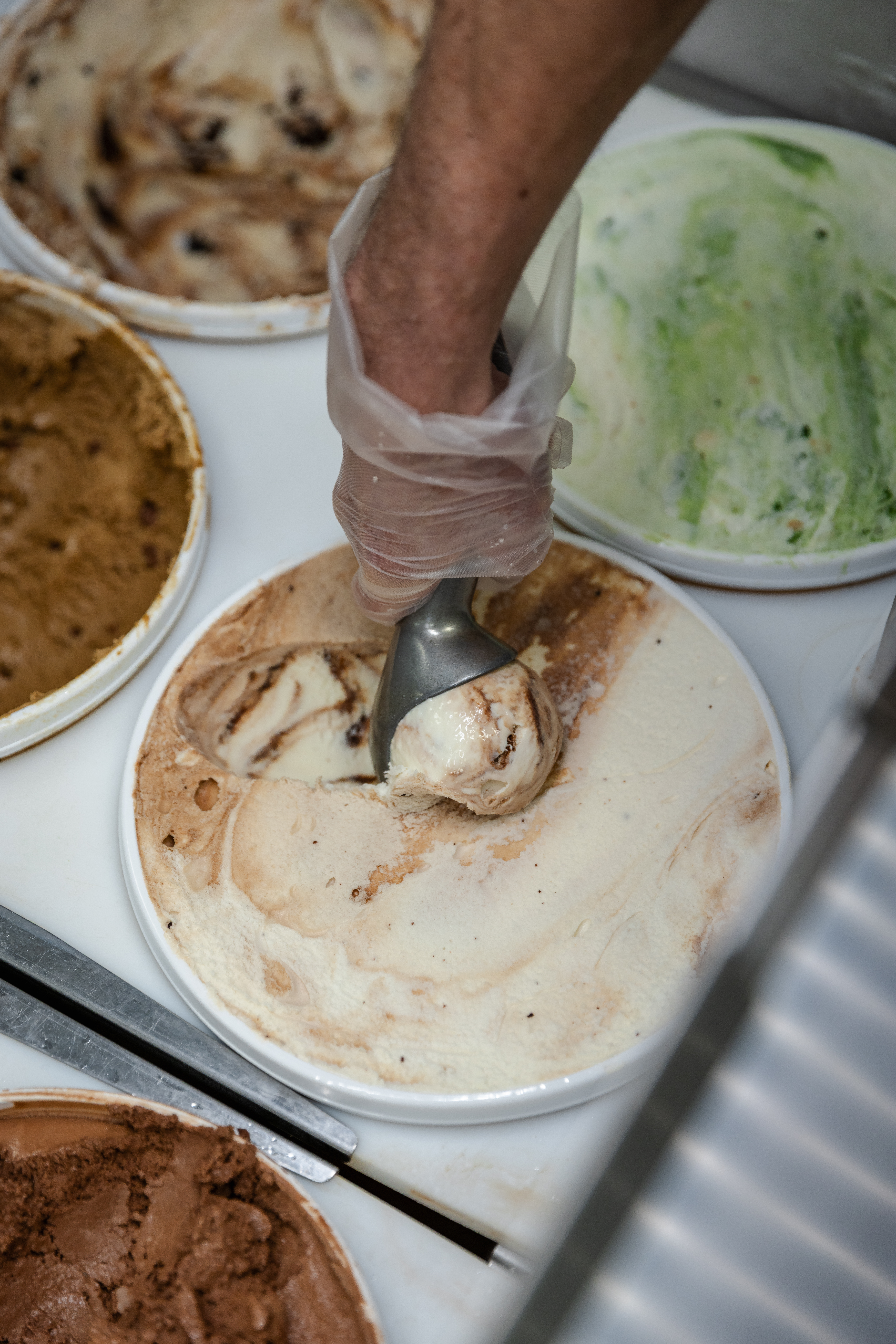 A worker digs into a fresh tub of Far Better Swirl'd, a new Dairy Store flavor celebrating the campaign, Uncommon Will. Far Better World. with an ice cream scooper