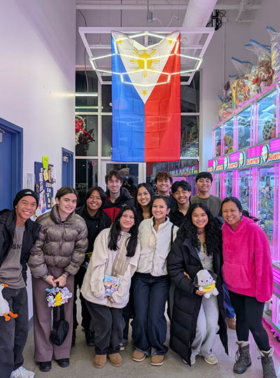 MSU students from the Pilipino American Student Society take a group photo in front of the claw machines at Klawsome in Novi along with co-owner and Spartan alum Agnes Filipowski. Above the group is the flag of the Philippines.