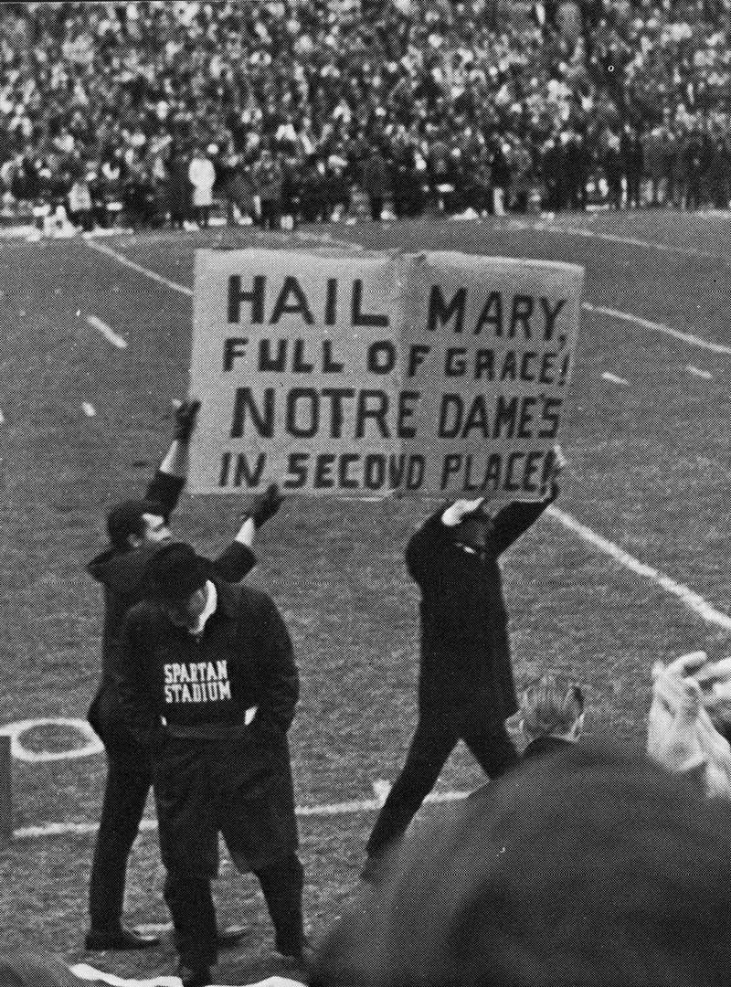 A black and white photo from 1966 shows Michigan State students on the sidelines holding up a sign that reads 