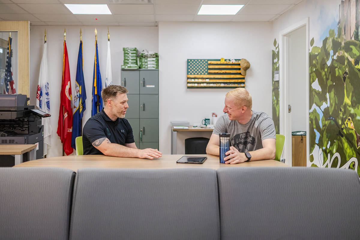 CVMAS director Patrick Forystek (left) and a veteran sit across from each other at a wooden table inside MSU's Center for Veterans and Military Affiliated Students.
