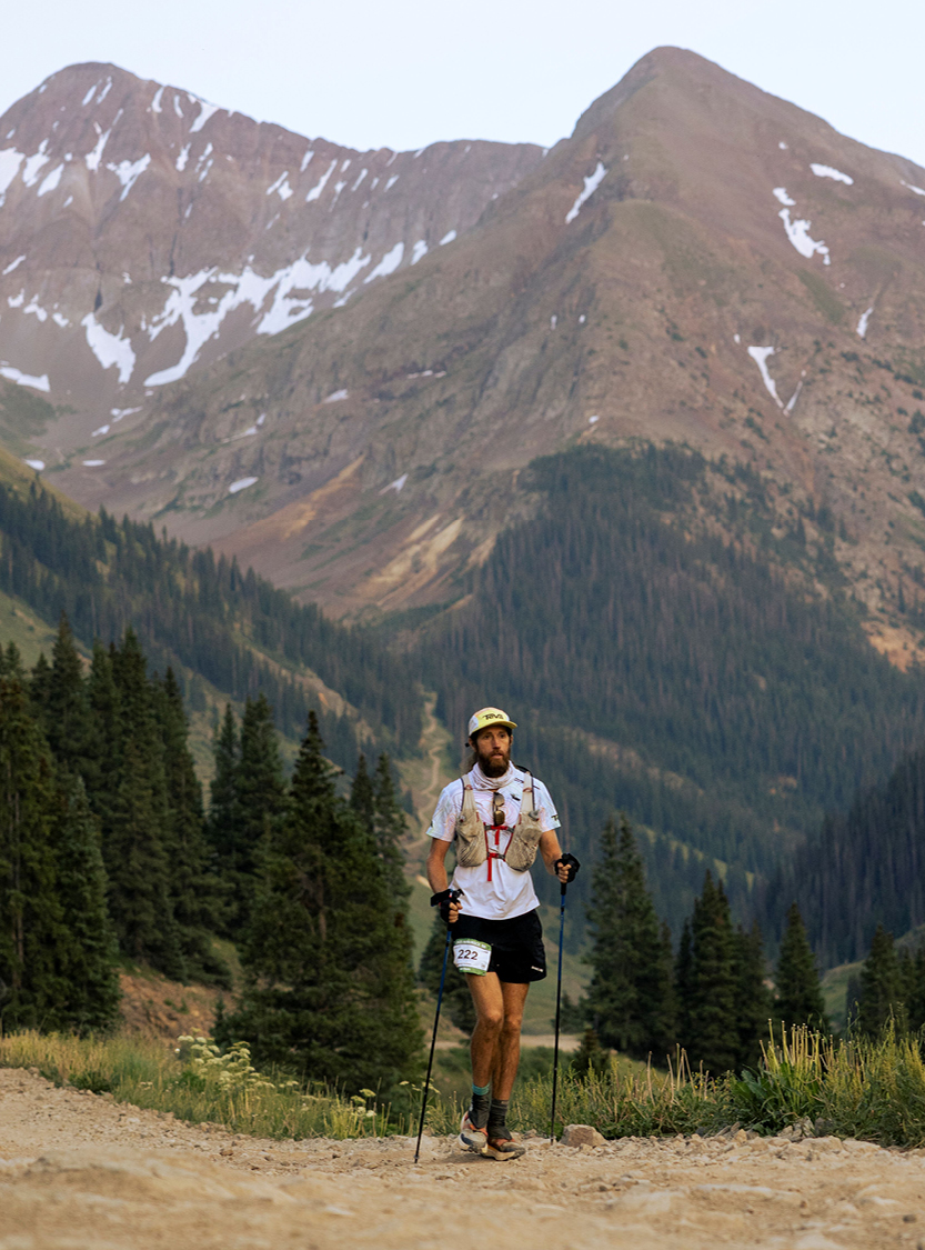 Mike Wardian Running through a mountain valley with peaks in the background. 