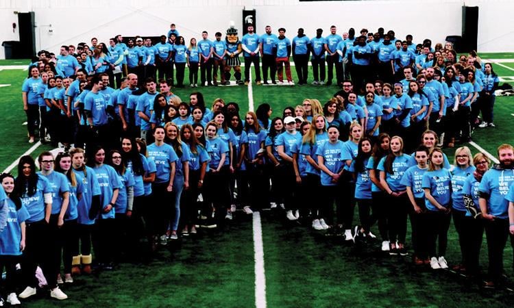 Students standing in a shape of a ribbon