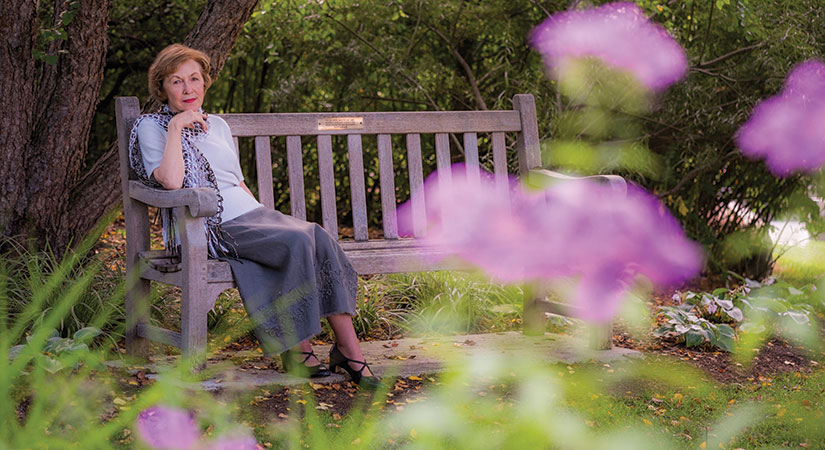 judy delapa poses on a bench in one of MSU's gardens